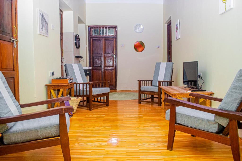 sala de estar con sillas y suelo de madera. en Zanzibar Spice Nest Apartment, en Stone Town