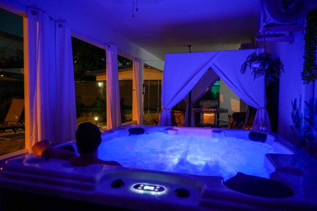 a man sitting in a jacuzzi tub in a house at night at Private Oasis with Jacuzzi and Cabana Pet Friendly in San Juan