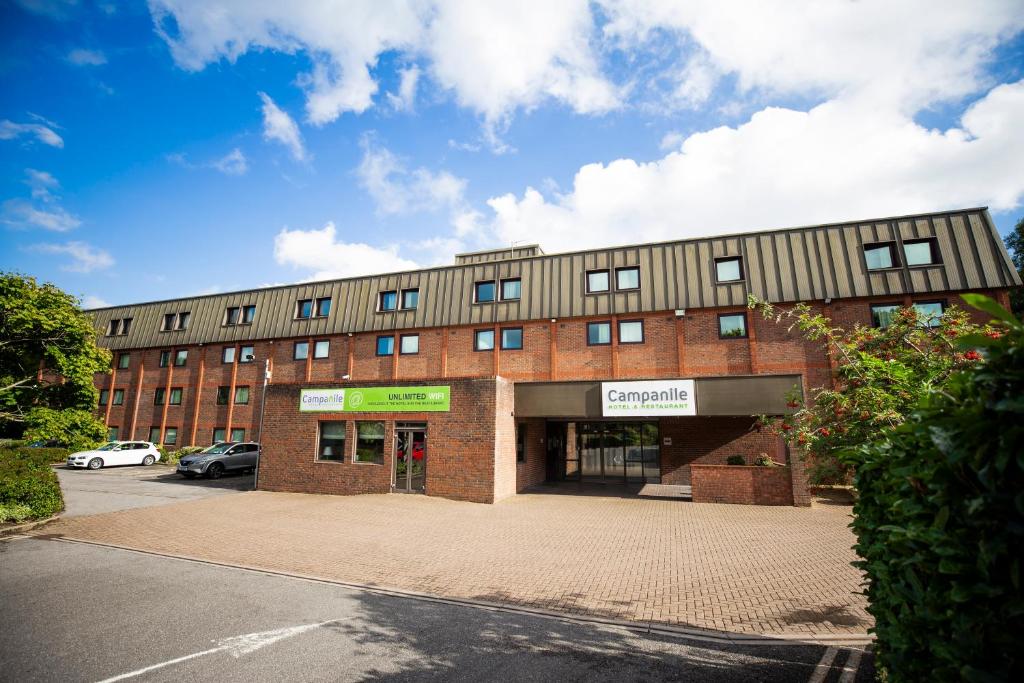 un gran edificio de ladrillo con un estacionamiento delante de él en Campanile Swindon en Swindon