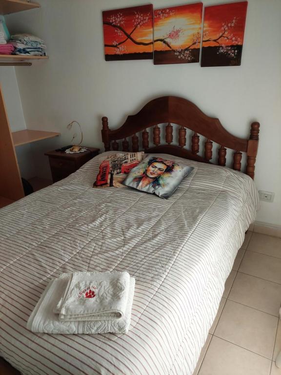 a bed with a wooden headboard and a towel on it at Habitación Privada en La Casa de Thor in Trelew