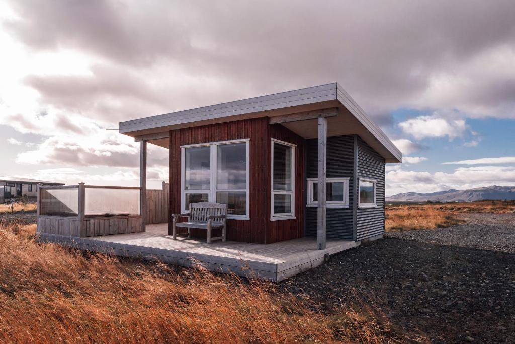 eine kleine Kabine mit einer Bank auf einem Feld in der Unterkunft Blue View Cabin 7B With private hot tub in Selfoss