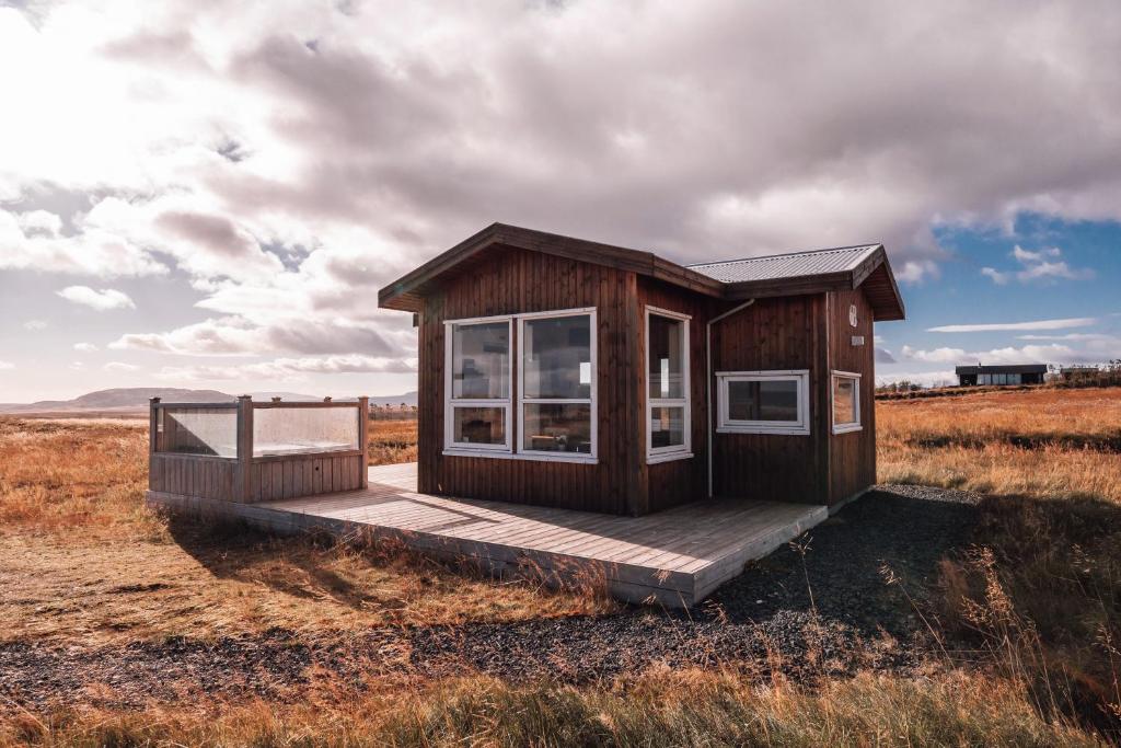 een klein huisje op een houten terras in een veld bij Blue View Cabin 6B With private hot tub in Reykholt