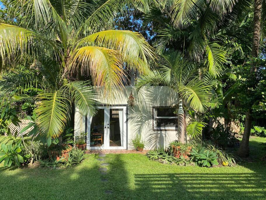 a white house with palm trees in front of it at Miami guest house with large pool in Miami