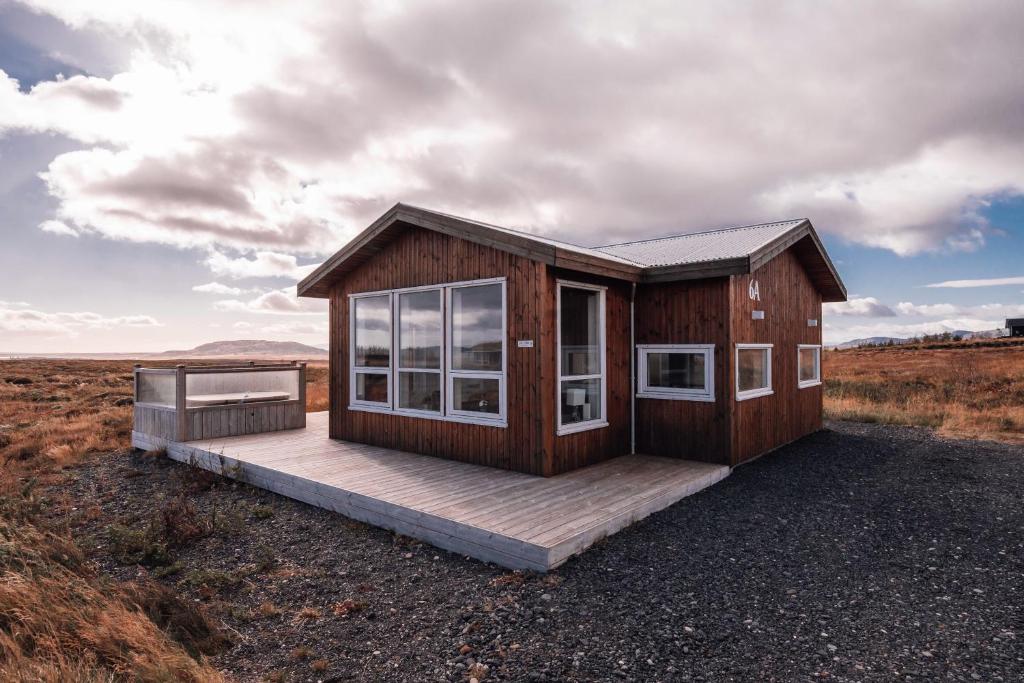 ein winziges Haus mit einer Terrasse auf einem Feld in der Unterkunft Blue View Cabin 6A With private hot tub in Reykholt