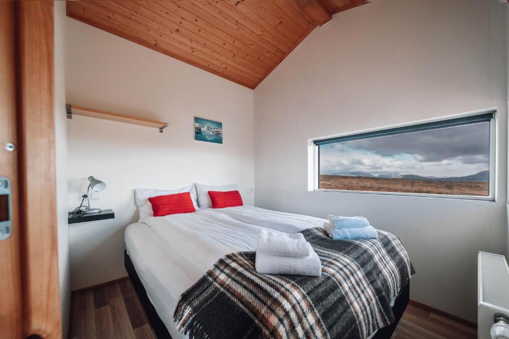 a bedroom with a large bed and a window at Blue View Cabin 1B With private hot tub in Reykholt