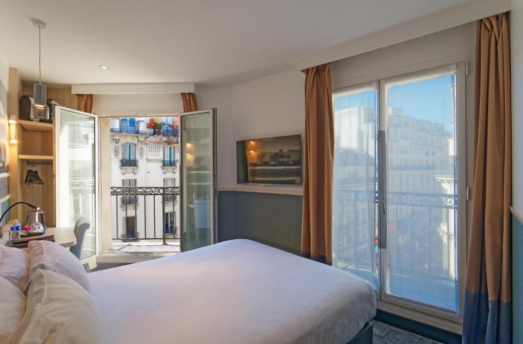 um quarto de hotel com uma cama e uma grande janela em Appia La Fayette em Paris