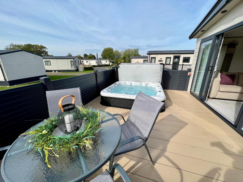 patio con mesa y terraza con bañera de hidromasaje. en Sunflower Hot Tub Lodge, en South Cerney