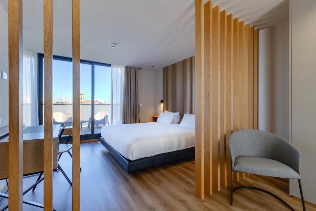 Habitación de hotel con cama, escritorio y silla en room Select Porto, en Oporto