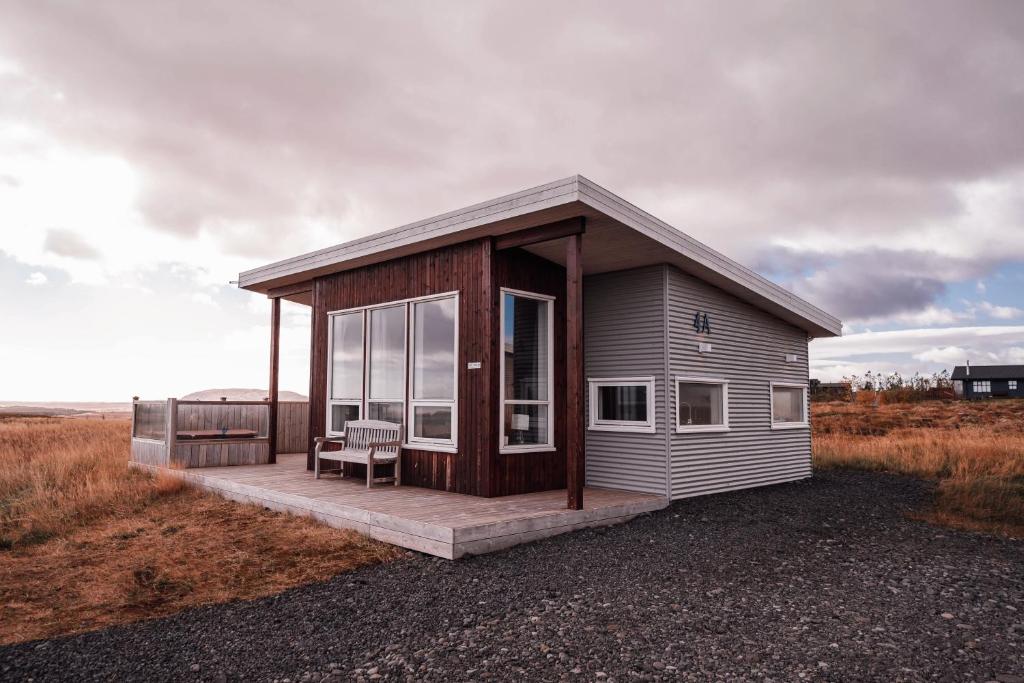 una pequeña casa con un banco en un campo en Blue View Cabin 4A With private hot tub, en Reykholt