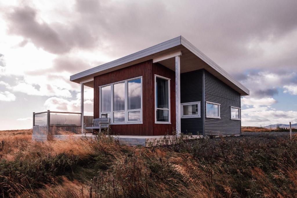 a small house sitting on top of a field at Blue View Cabin 7A With private hot tub in Reykholt