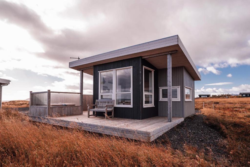 una pequeña casa con un banco en la cubierta en Blue View Cabin 3B With private hot tub, en Reykholt