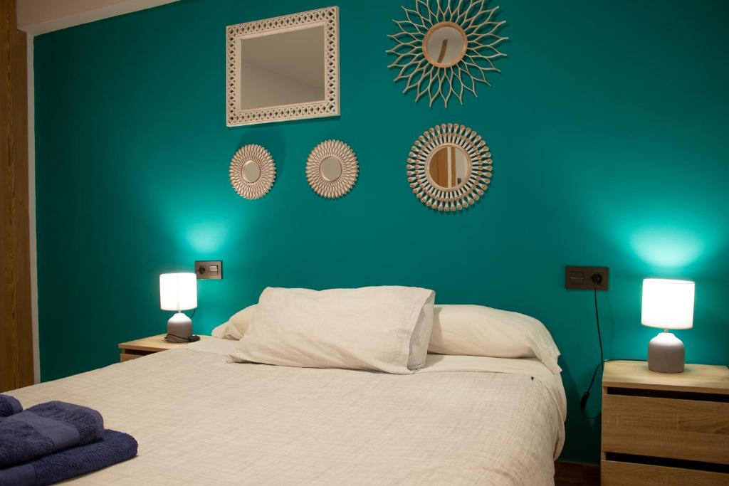 1 dormitorio con una pared verde, 1 cama y 2 lámparas en Piso para cuatro a los pies de la Alhambra, en Granada
