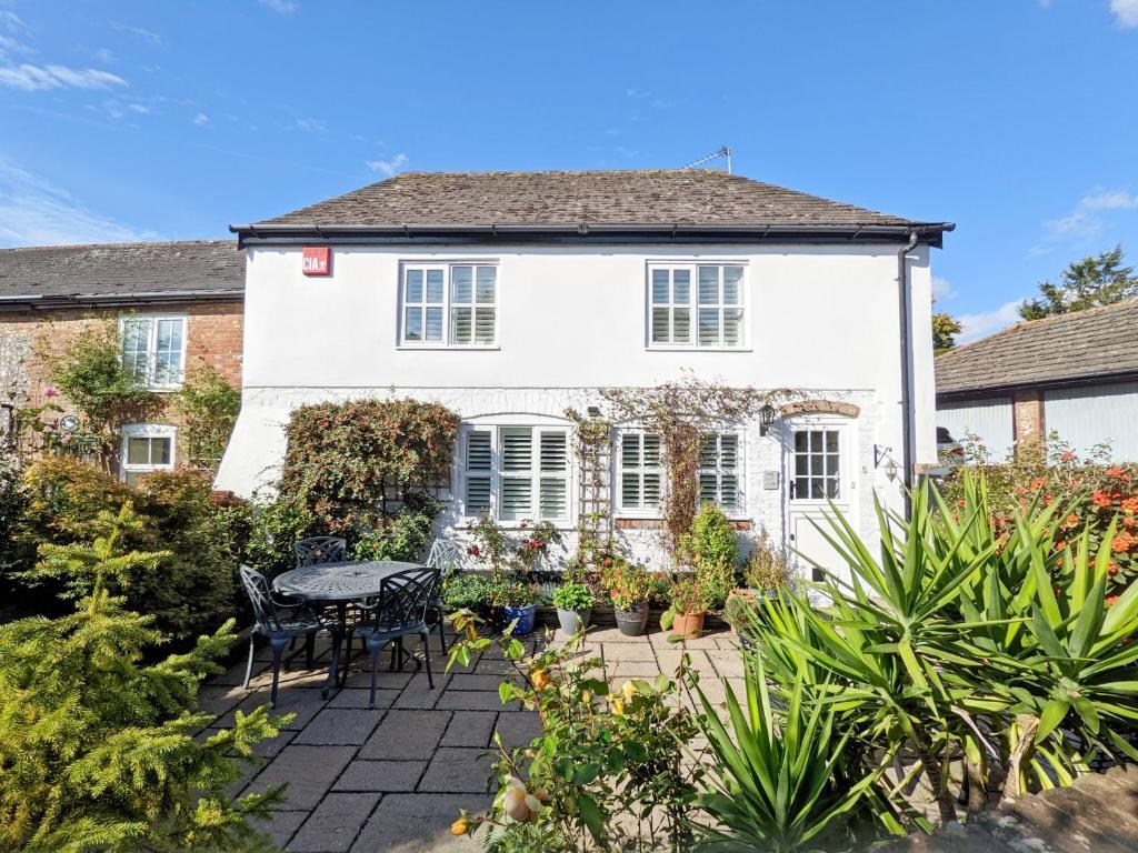 a white house with a table and chairs in the garden at Baytree Cottage, Walberton in Walberton