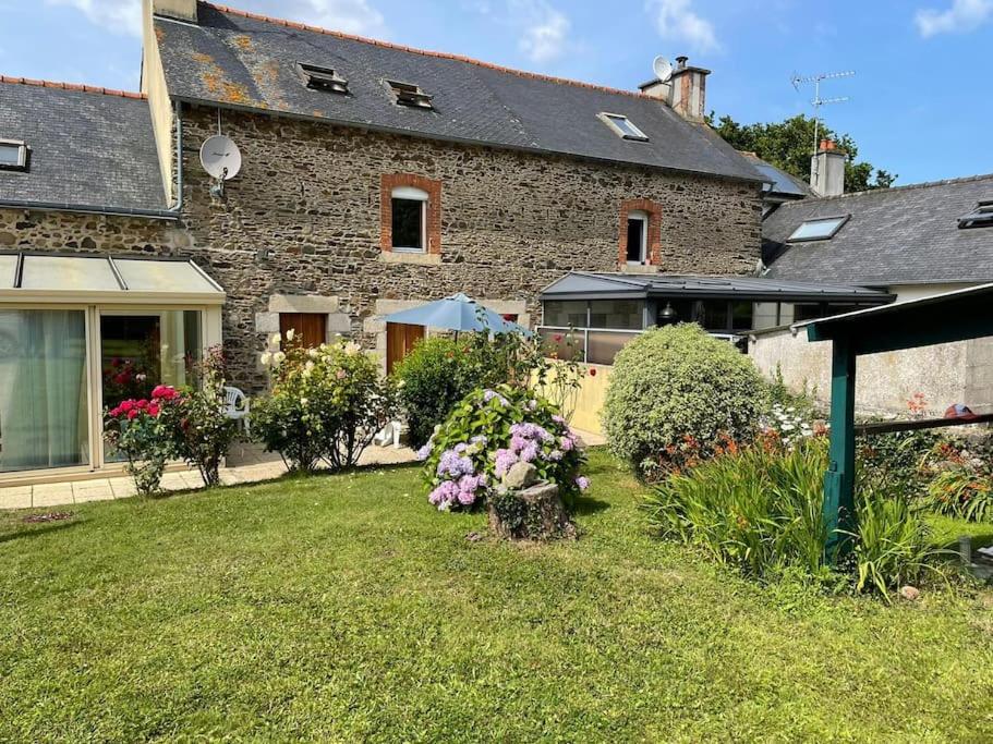 une maison avec une cour fleurie devant elle dans l'établissement Maison de famille entre terre et mer, à Lantic