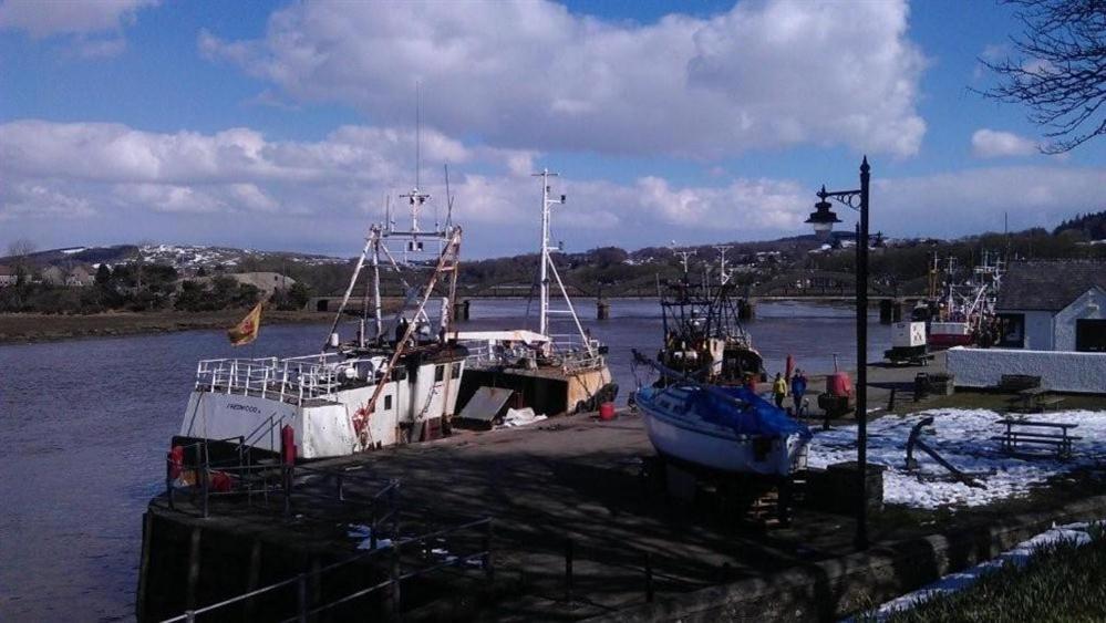 two boats are docked at a dock in the water at 26 Castle Street in Kirkcudbright