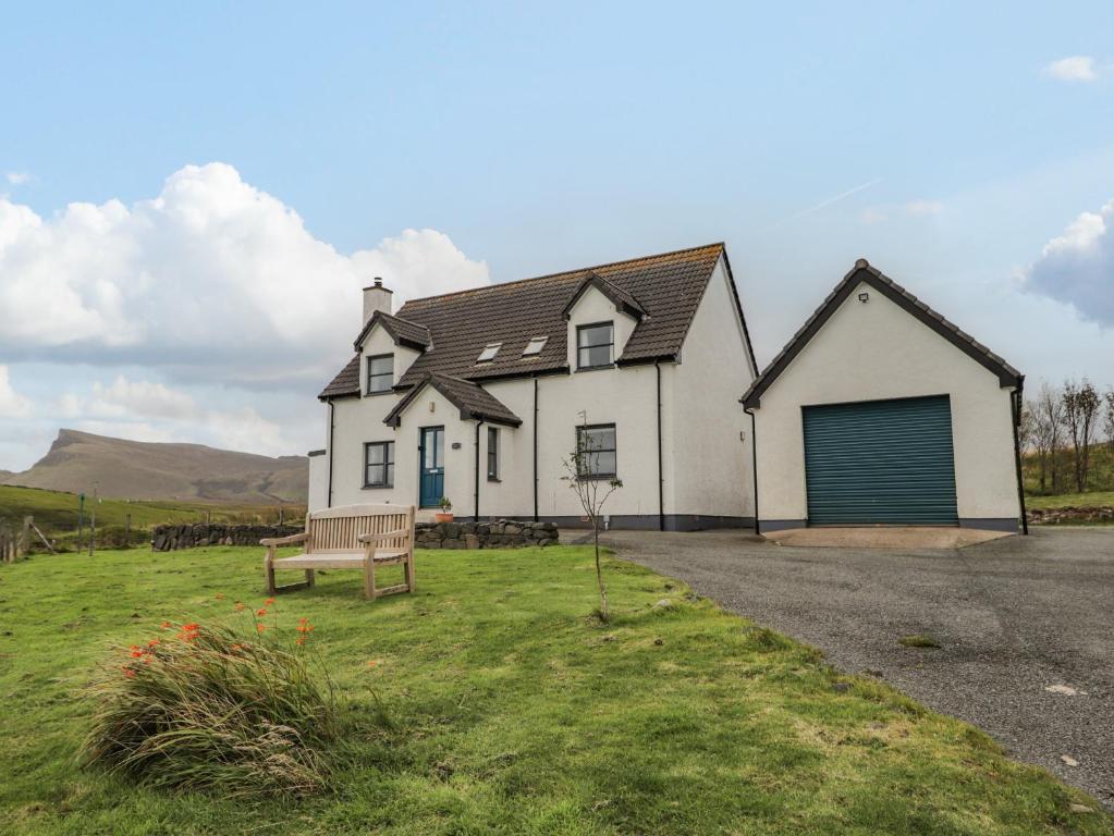 a white house with a bench in front of it at Hilltop House in Staffin