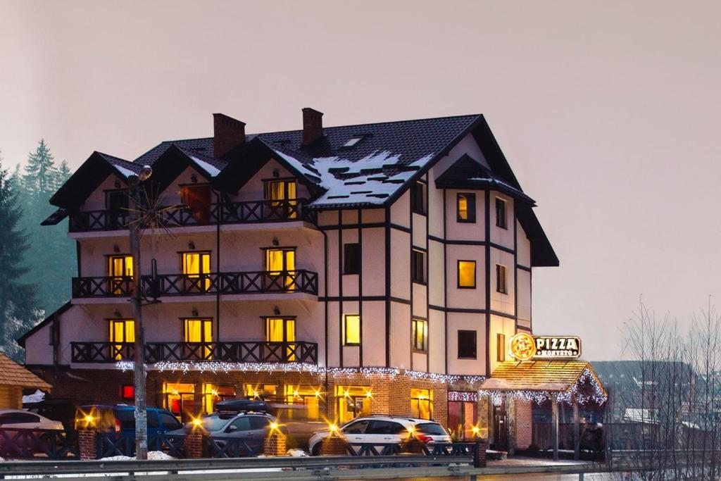 una grande casa con macchine parcheggiate di fronte di Hotel Monysto a Bukovel