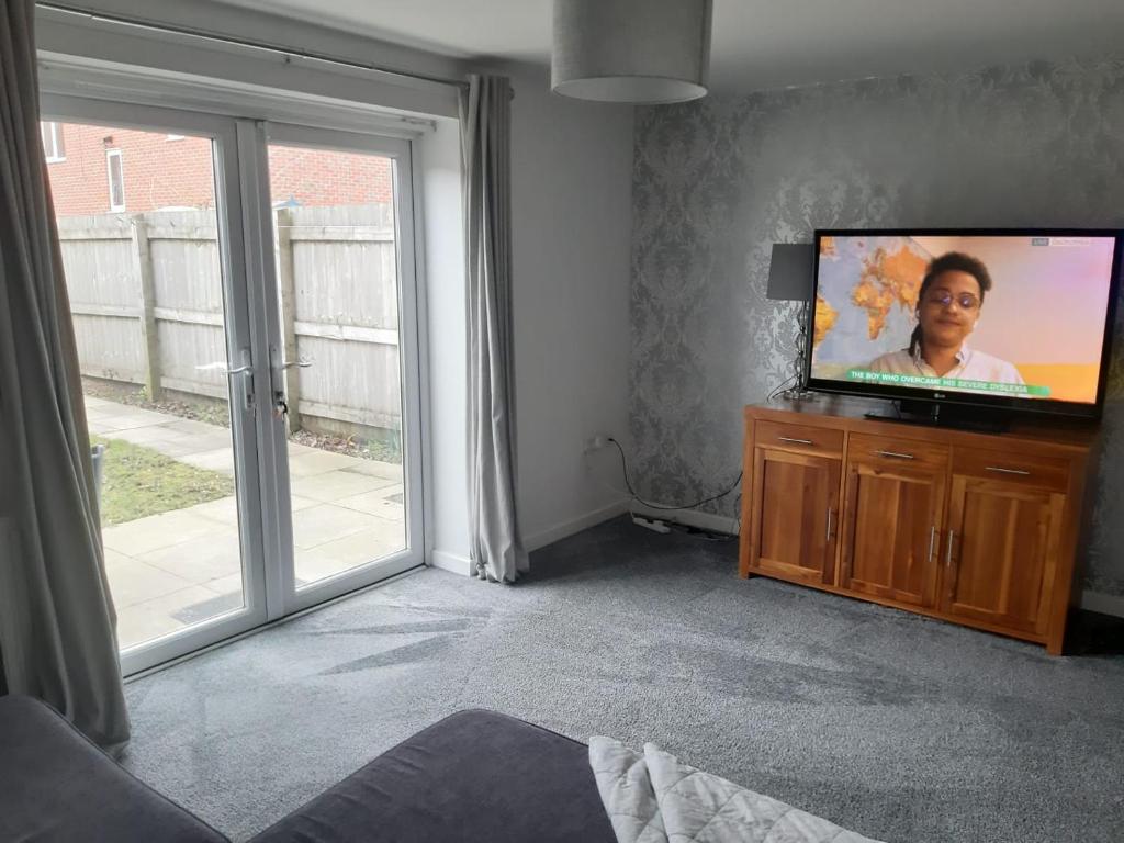 a living room with a flat screen tv on a dresser at 3 bedroom, 3 story town house in Liverpool