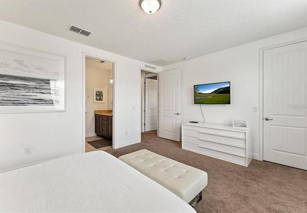 a white bedroom with a bed and a tv at 371 P Luxury Villa- New Listing in Orlando
