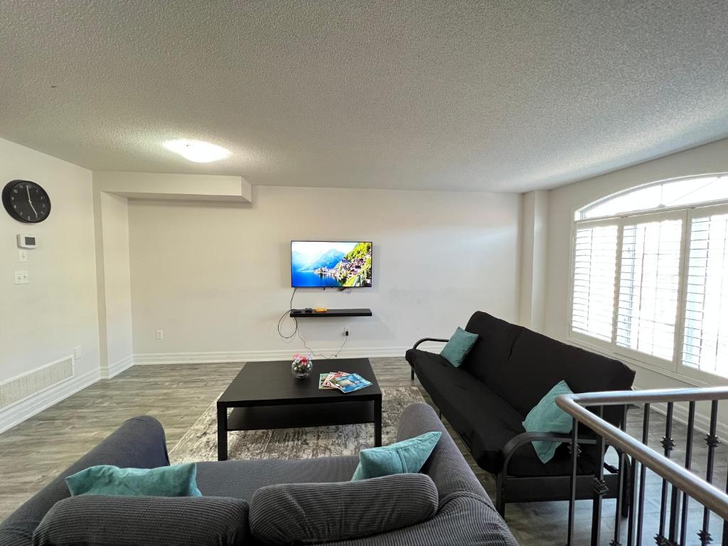 a living room with a couch and a tv at Beautiful Vacation Home near Toronto Airport in Mississauga