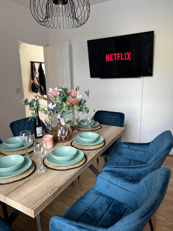 a dining room table with blue chairs and a table with plates at Cheerful 5 Bedrooms & En-Suite Bathrooms Town House in Northampton