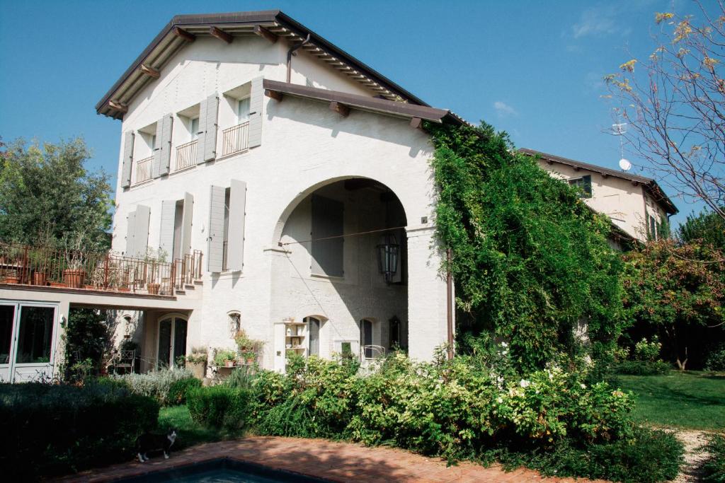 ein weißes Haus mit einem Torbogen und Efeu in der Unterkunft Casale Hortensia in Reggio nell'Emilia