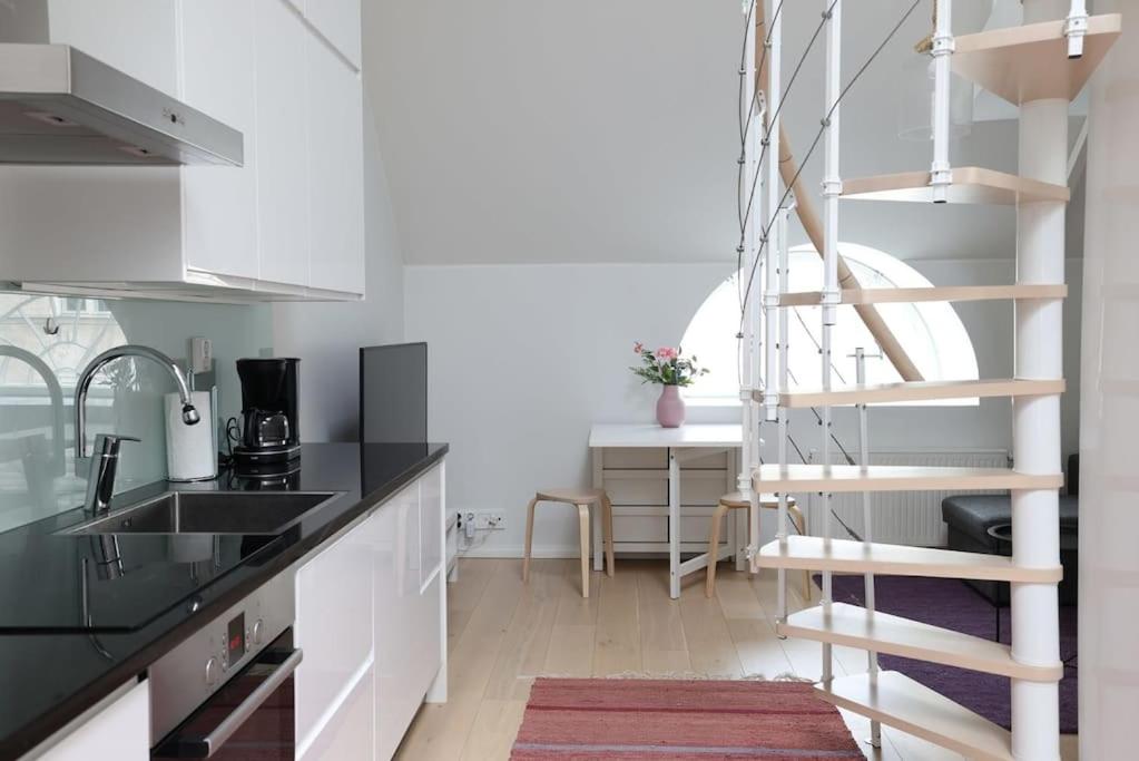 a kitchen with white cabinets and a spiral staircase at 2ndhomes Unique 35m2 Studio Penthouse with Sauna & Balcony in Helsinki
