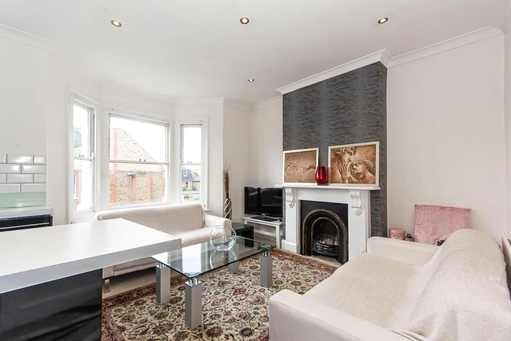 a living room with white furniture and a fireplace at Lovely place, perfect for family and business travellers ideally located between the commons in London