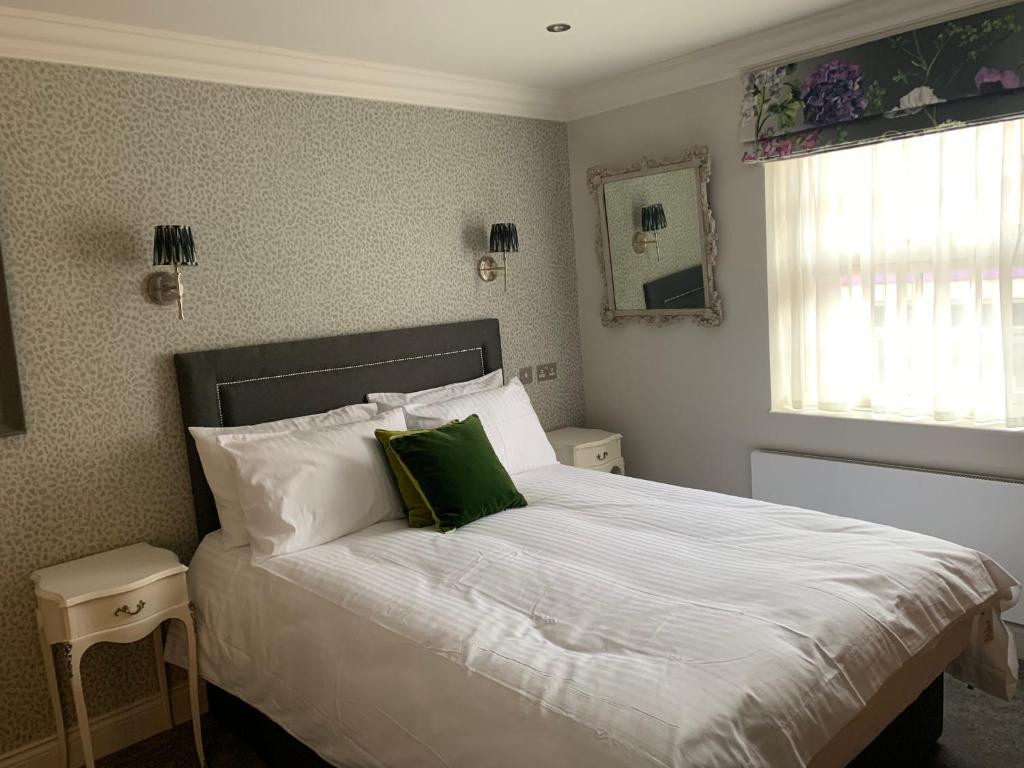 a bedroom with a white bed with a green pillow at The Pig and Whistle in London