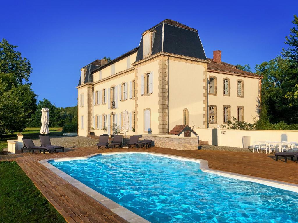 una casa grande con piscina frente a ella en Chateau de la Coutere en Saint-Laurent