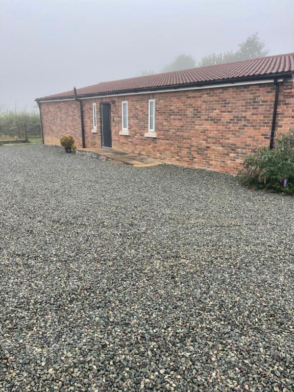 a brick building with a large gravel yard at Apple Barn Guest House in Wisbech