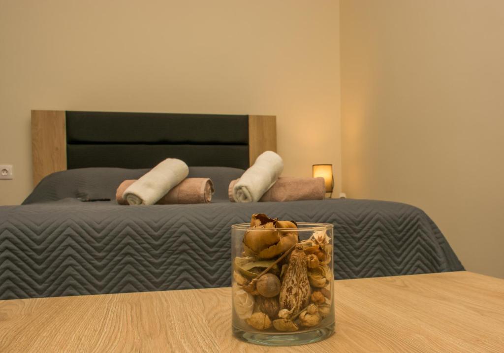 Central Luxury Studio 2 في كورينثوس: وجود مزهرية زجاجية على طاولة أمام السرير