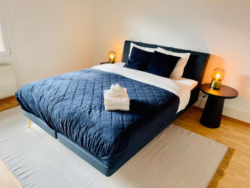 sypialnia z dużym niebieskim łóżkiem z 2 lampami w obiekcie -The Urbanist- Lakeview Free Parking 2BD Fast WiFi w mieście Oberhofen am Thunersee