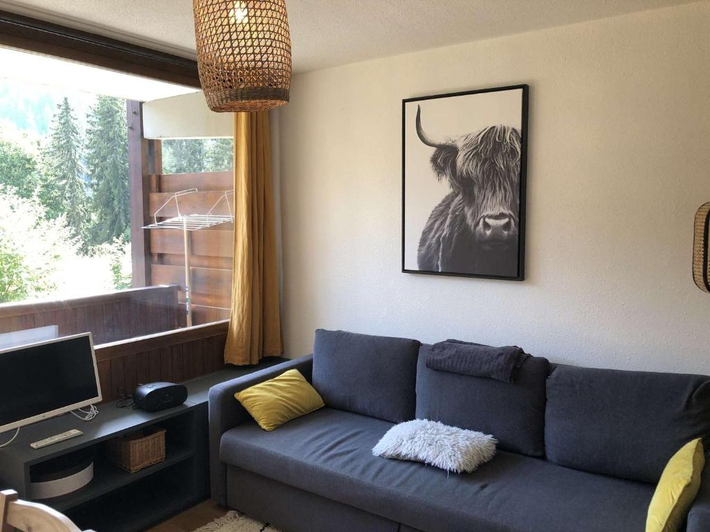 een woonkamer met een blauwe bank en een foto van een stier bij Appartement Crest-Voland, 1 pièce, 4 personnes - FR-1-595-59 in Crest-Voland