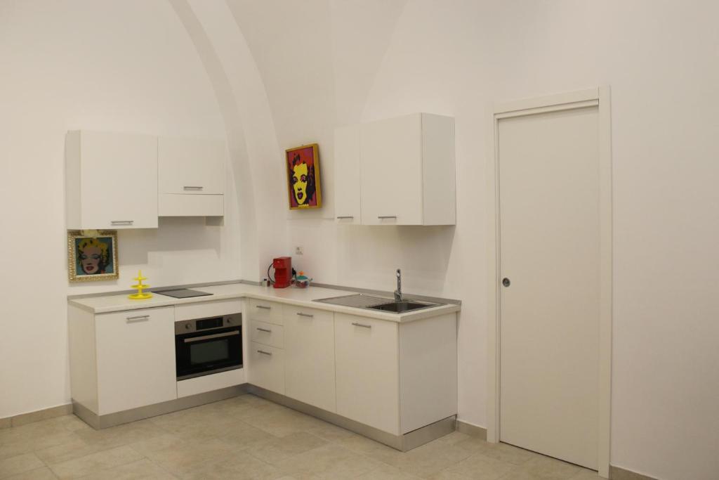 uma cozinha branca com armários brancos e um lavatório em B&b Bianco em Orta Nova