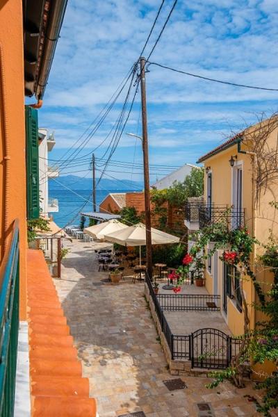 an empty street with tables and umbrellas next to buildings at Alekos House in Longós