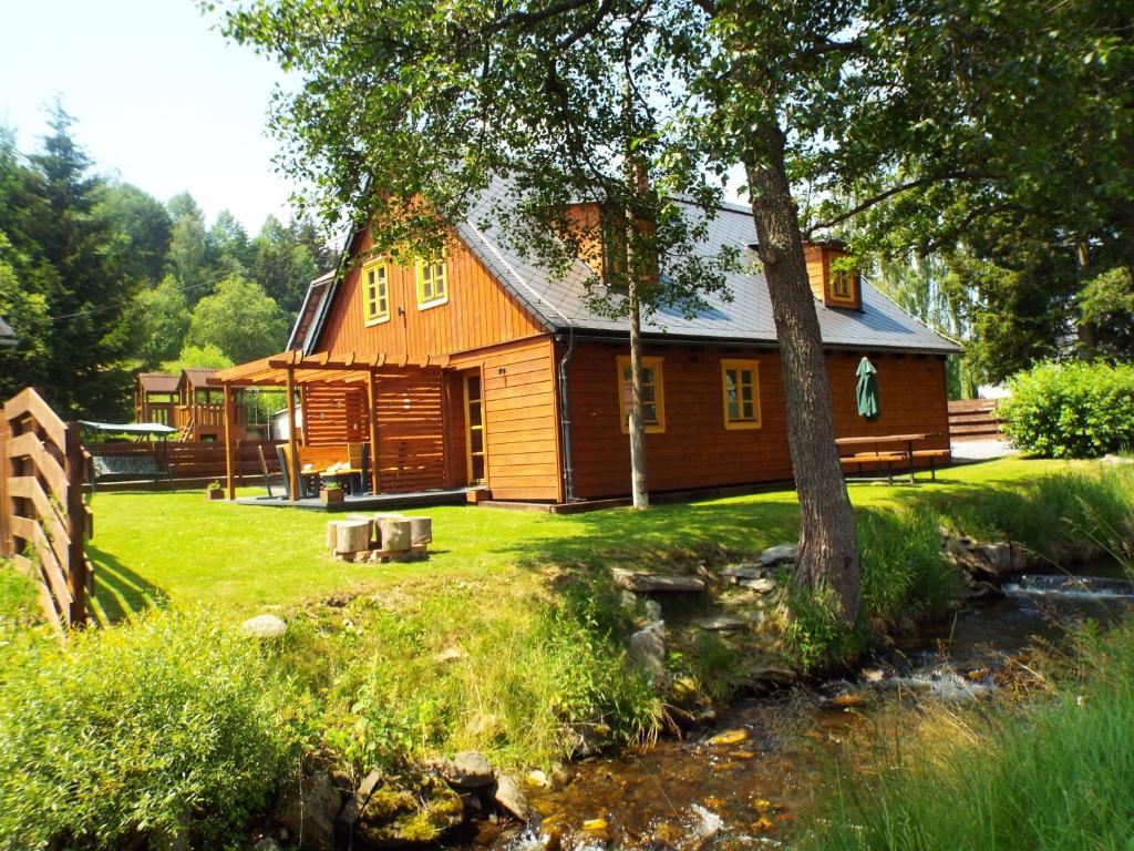 une cabane en rondins avec un ruisseau devant elle dans l'établissement Czech Lodge, à Stará Ves