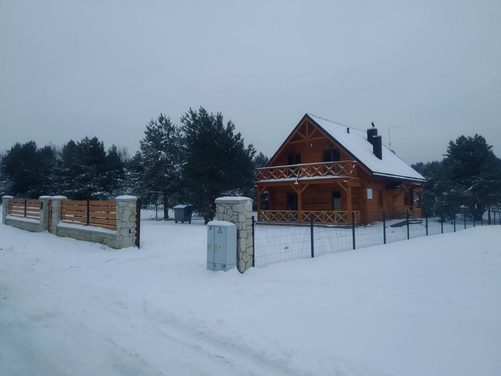 una cabaña de madera en la nieve con una valla en Chata Sosenka en Sygontka