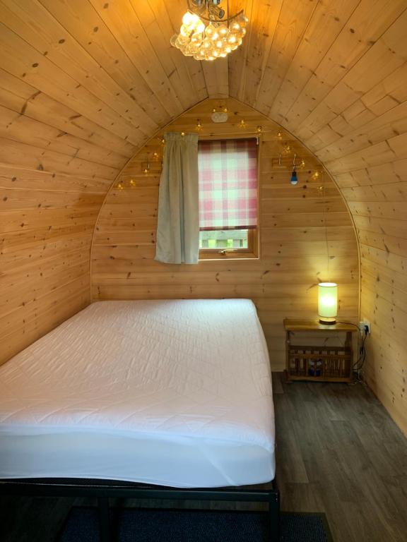 a bed in a wooden room with a window at Poplars Farm Site Glamping Pods in Hulland