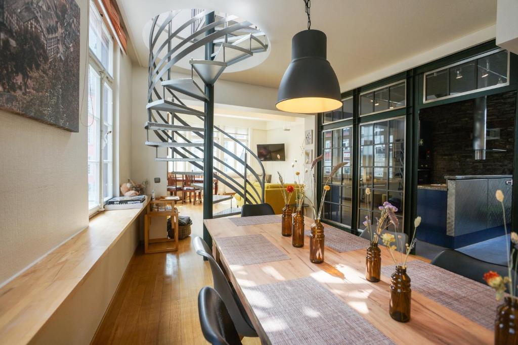 a dining room with a table and a spiral staircase at LOFT13 Traumhafte Wohnung mit Terrasse für 4 Gäste in Monschau