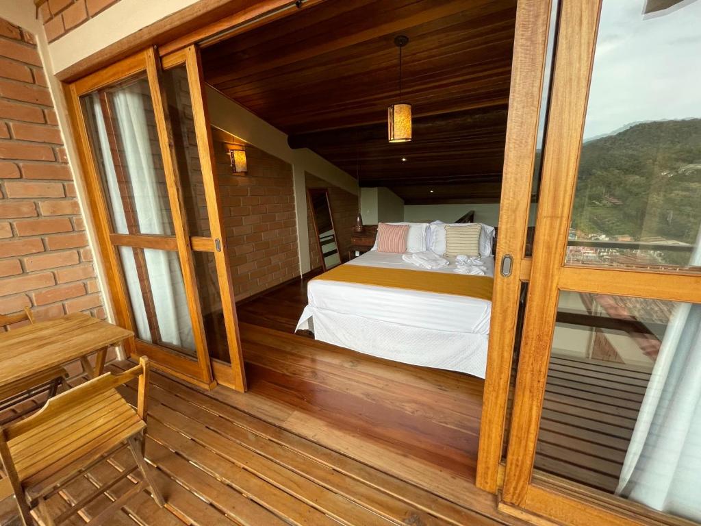Habitación con cama en un balcón de madera. en Loft Maika'i, en Santo Antônio do Pinhal