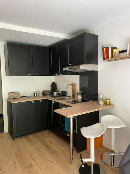 a kitchen with black cabinets and a wooden counter top at Agréable et moderne studio à Neuilly avec jardin in Neuilly-sur-Seine