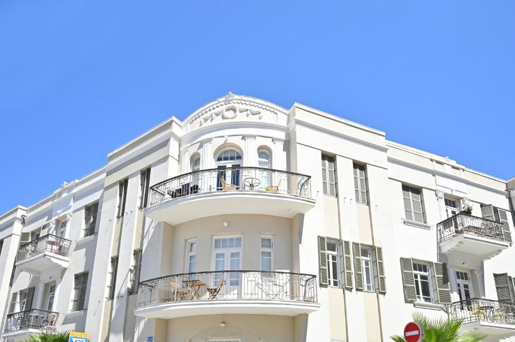 a white building with balconies and a blue sky at Bohemian Valse by HolyGuest in Tel Aviv