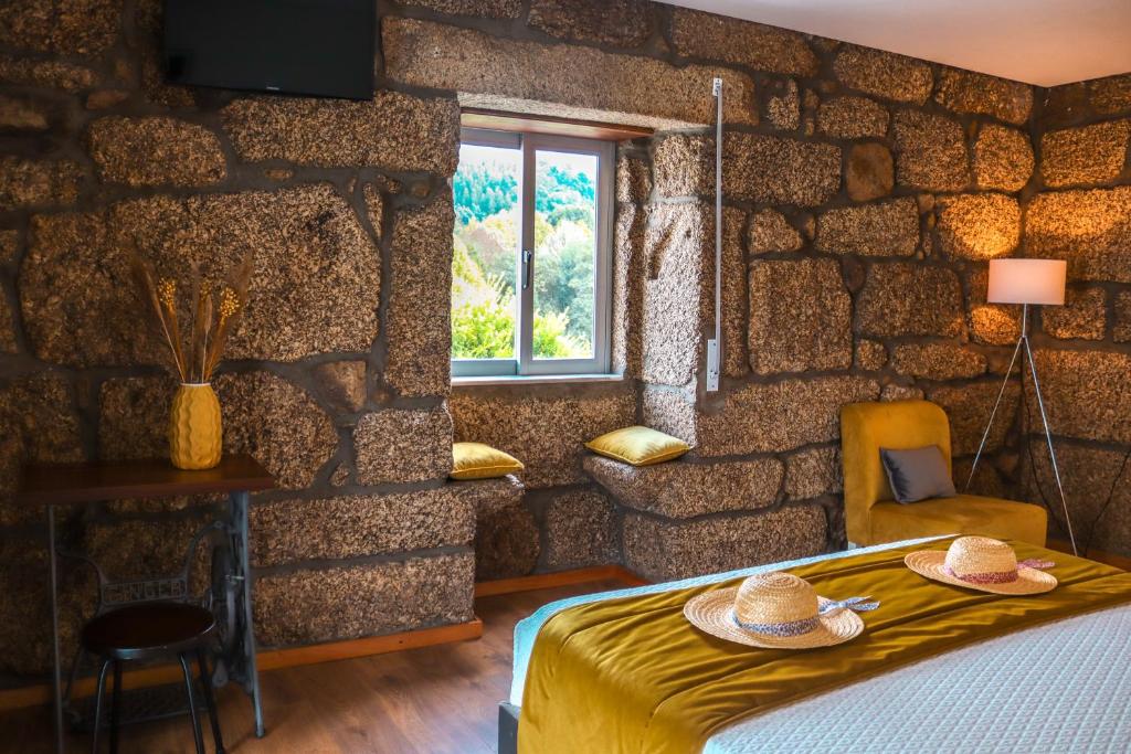 a bedroom with a stone wall with a bed and a window at Quinta de Requeixo in Guimarães