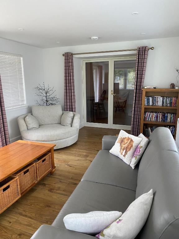 uma sala de estar com um sofá e uma mesa em Cosy Cottage in beautiful Royal Deeside em Aboyne