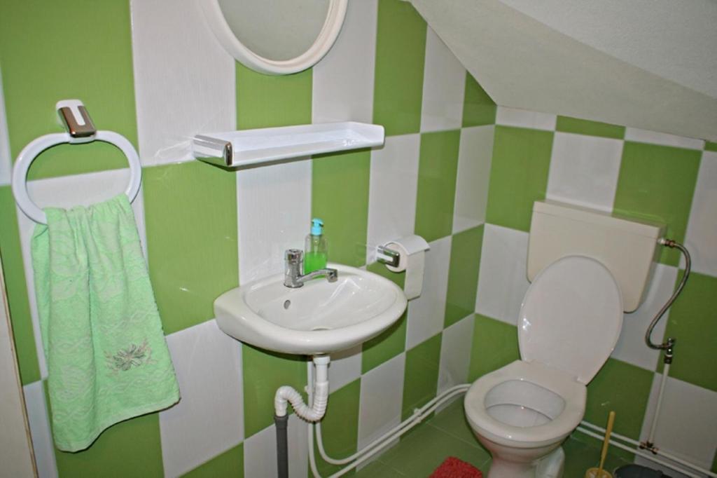 トゥルダにあるHelga Houseの緑と白のバスルーム(トイレ、洗面台付)
