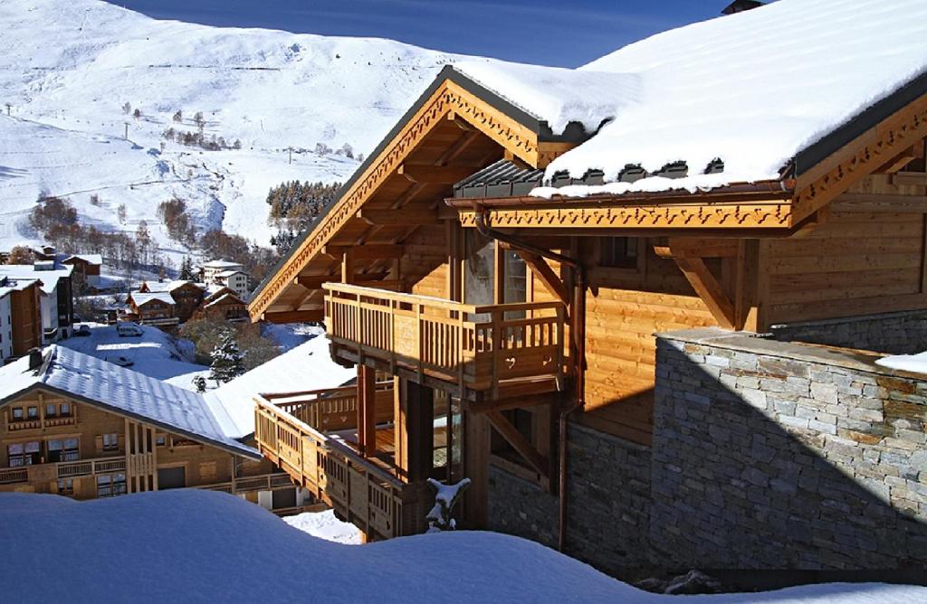 uma casa de madeira com neve no telhado em Odalys Chalet Husky em Les Deux Alpes