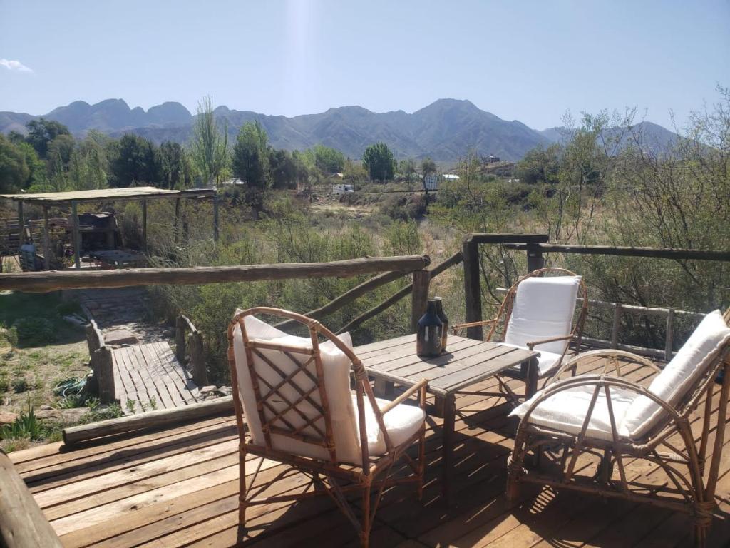 una mesa de madera y sillas en una terraza con vistas en Andes Sol y río cabañas vacacionales en la montaña mendoza en Las Compuertas