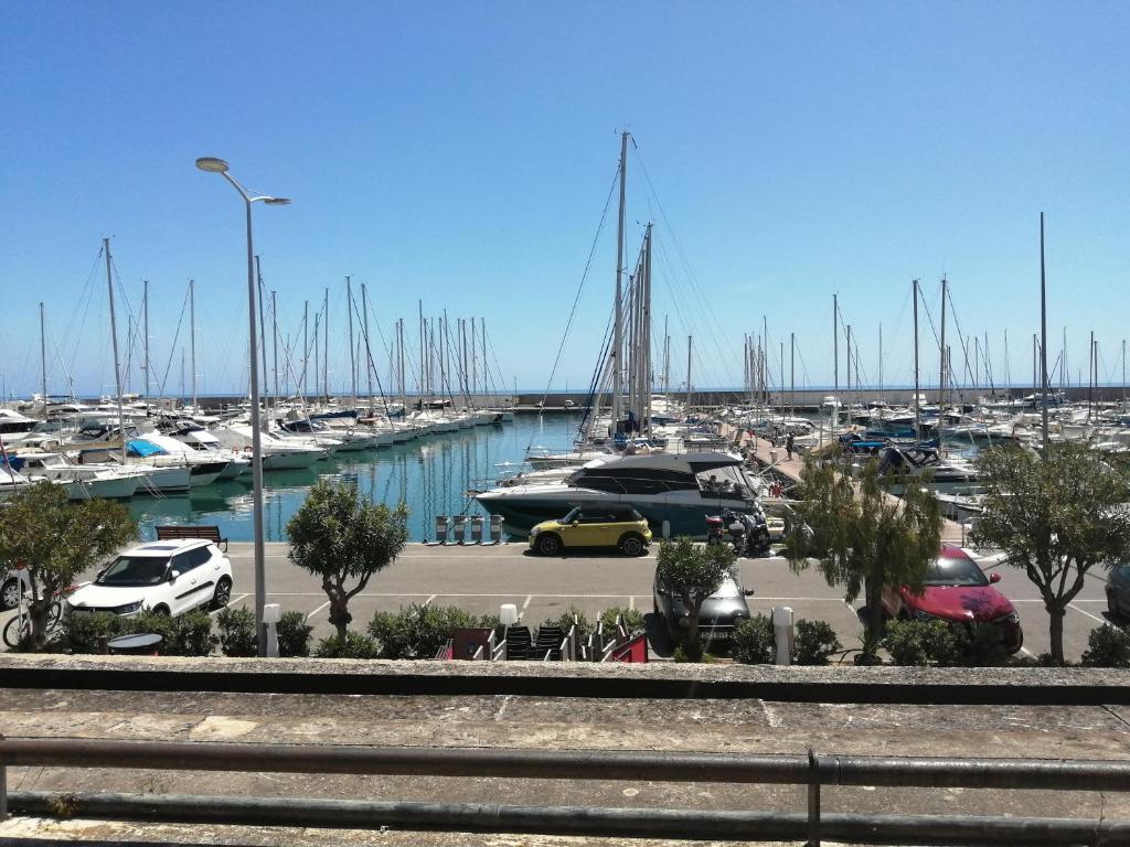 un port de plaisance avec des voitures garées dans un parking avec des bateaux dans l'établissement Joli studio bord de mer, clim, balcon, parking privé, à Menton