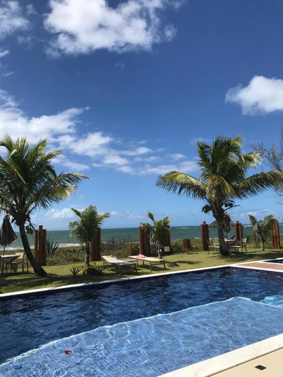 a swimming pool with a view of the beach at Novíssimo Village Beira Mar in Itacimirim